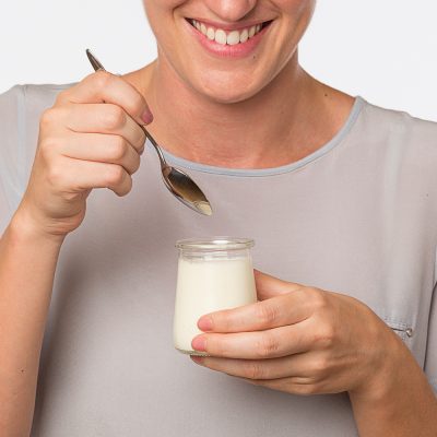 Jeune femme s'appretant a déguster un yaourt le petit basque pot en verre transparent et plonger sa cuillere dans le pot