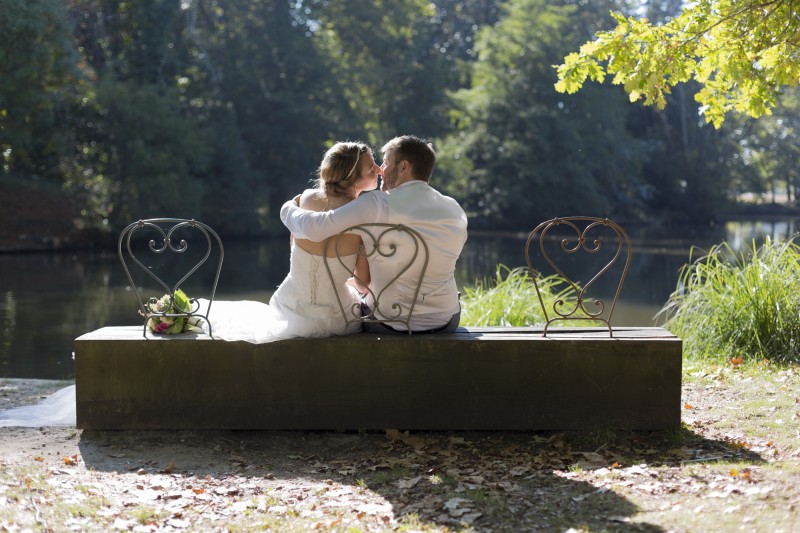 Maries qui s'embrassent sur un banc devant un étang mariage bordeaux photos sebastien huruguen photographe banc majolan parc blanquefort amour love kissing bisous couple de jeunes mariés dans le parc majolan a Blanquefort seance photo mariage trash the dress par Sebastien Huruguen photographe de mariage a Bordeaux