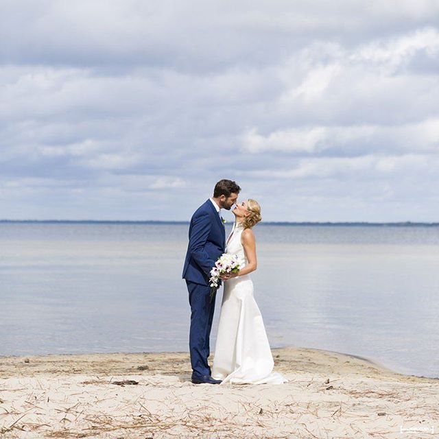 Couple de jeunes mariés s'embrassant au bord de l'eau au lac de Carcans Maubuisson en Gironde
