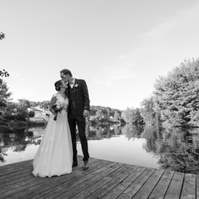 Couple de jeunes mariés s'embrassant sur un ponton du jardin de l'hotel Quai des Pontis au bord de la charente à Cognac sous l'oeil du photographe de mariage bordelais Sébastien Huruguen