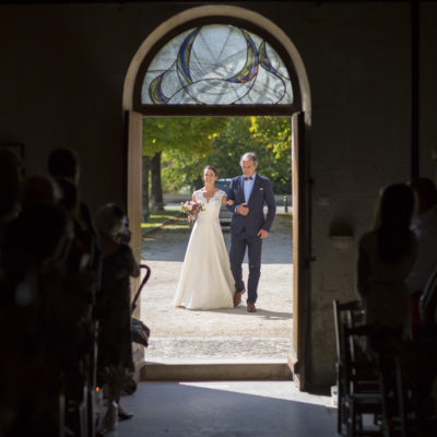La mariée arrivant au bras de son père à l'entrée de l'église pour la cérémonie religieuse de son mariage à Cognac en Charente.